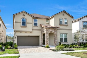 A two-story house with a stone facade, a garage, and a well-maintained front yard.