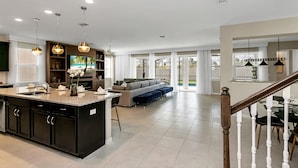A spacious living area with a large island, dark cabinetry, and a staircase leading to another level. - 1798cvt Solara Resort 9 Bedroom 6 Bathroom Villa (Kissimmee)