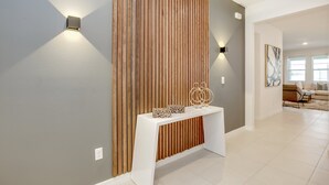 Un interior moderno con una pared de acento de madera, una consola blanca y un sofá al fondo.