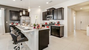 Una cocina moderna con una isla central, armarios oscuros y electrodomésticos de acero inoxidable.