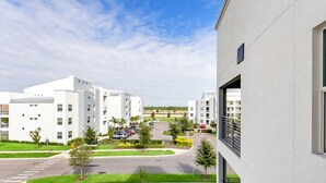 A modern residential building with multiple floors, a parking area, and a well-maintained lawn. - 3111u307 Amazing Story Lake Brand New Condo (Kissimmee)