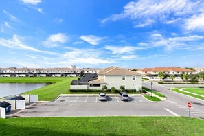 A parking lot with several cars, a stop sign, and a building with a green lawn in the foreground. - 3111u307 Amazing Story Lake Brand New Condo (Kissimmee)