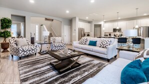 A spacious living room with a sofa, coffee table, and a dining area with a chandelier. - Broad Oak Villa Solterra 3 (Davenport)