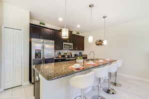 Uma cozinha moderna com armários escuros, eletrodomésticos de aço inoxidável e bancada de granito.