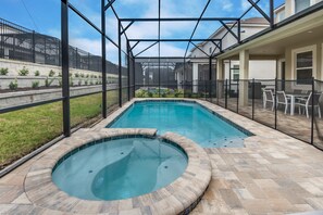 A swimming pool with a hot tub, surrounded by a covered patio area with outdoor furniture. - 1780spp New 7 Bedroom 5 Bathroom Solara Villa (Kissimmee)
