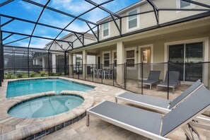 A swimming pool with a hot tub, surrounded by lounge chairs and a covered patio area. - 1780spp New 7 Bedroom 5 Bathroom Solara Villa (Kissimmee)