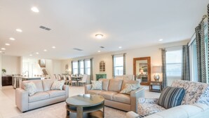 A spacious living room with a large round coffee table, two sofas, and a dining area in the background. - Falls Drive Reunion (Kissimmee)