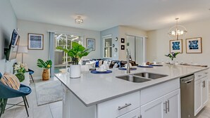 Une cuisine moderne dotée d’un grand îlot central, de meubles blancs et d’appareils électroménagers en acier inoxydable.