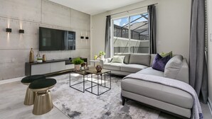 Ein modernes Wohnzimmer mit einer Couch, einem Couchtisch und einem an der Wand befestigten Fernseher.