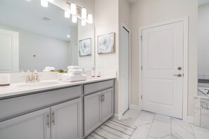 Un bagno moderno con uno specchio grande, sanitari bianchi e una porta.