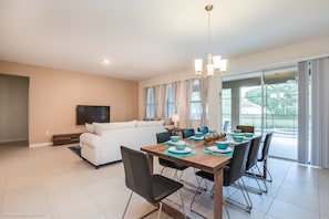 A modern living room with a white sofa, a dining table set with blue and white dishes, and a TV mounted on the wall. - Oakbrone Avenue Villa Solterra 3 (Davenport)