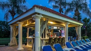 A covered outdoor seating area with blue lounge chairs and a bar. - 2782skp Emerald Island Resort (Kissimmee)