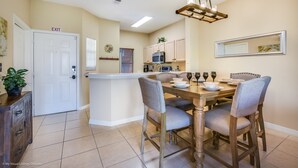 A dining area with a wooden table, grey upholstered chairs, and a pendant light. - 2782skp Emerald Island Resort (Kissimmee)