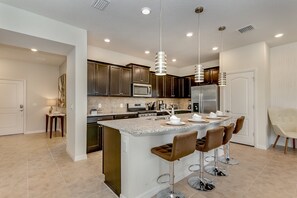 A modern kitchen with a central island, stainless steel appliances, and pendant lighting. - 4594terra (Davenport)