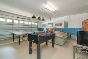 A room with a foosball table, a sofa, a television, and a window with blinds. - 234glen Fantastically Decorated 4 bed 2 Bath (Davenport)