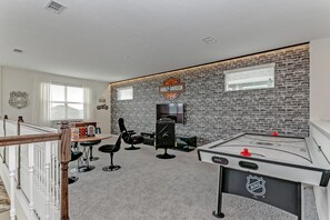 Ett rum med en tegelvägg, en skylt med Harley-Davidson-logotypen, en tv och ett bord för bordsfotboll.