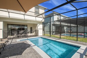 A swimming pool with a glass enclosure, patio furniture, and a covered seating area. - 8916sydney Fantastic 5 Bed 4 Bathroom Town Home (Kissimmee)