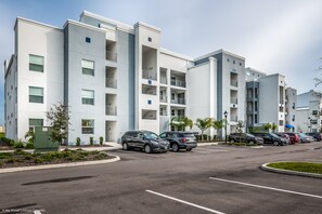 A modern multi-story residential building with a parking lot. - 4741ct Unit101 Amazing Story Lake Brand New Condo (Kissimmee)