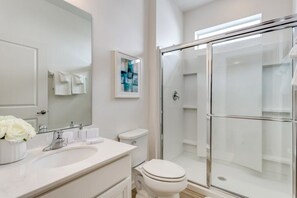 A modern bathroom with a large mirror, white fixtures, a glass shower enclosure, and a framed artwork on the wall. - 518mb New and Modern 8 Bedroom 5 Bathroom Villa (Kissimmee)
