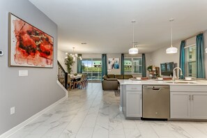 Eine moderne Küche mit einer zentralen Kochinsel, Edelstahlgeräten und einem Essbereich mit einer Treppe, die auf einen Balkon führt.