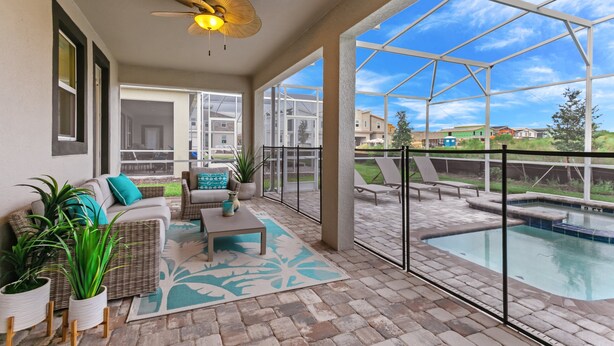 A covered patio with a pool, outdoor seating, and large windows.