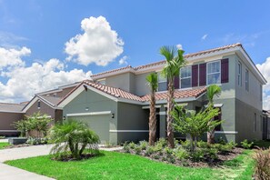 A modern two-story house with a tiled roof, a well-maintained lawn, and several palm trees. - Broadaok Drive Villa Solterra 6091 (Davenport)