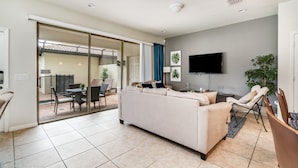 A modern living room with a sofa, TV, and a sliding glass door leading to an outdoor patio.