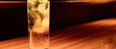Un vaso de agua con hielo y hojas de menta sobre un posavasos de madera.