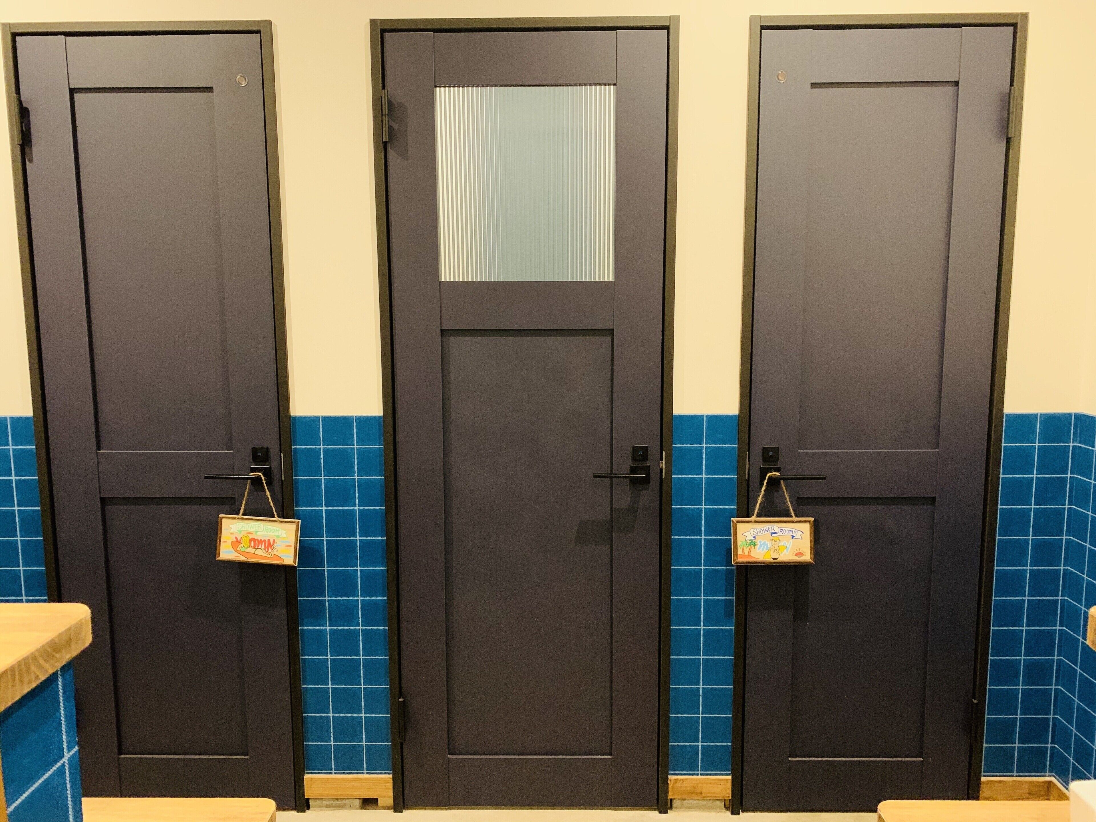 Tres puertas oscuras con manijas, cada una con un pequeño cartel colorido colgando debajo.