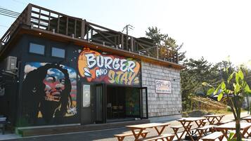 A building with a mural, outdoor seating, and a sign that reads "Burger and Stay".