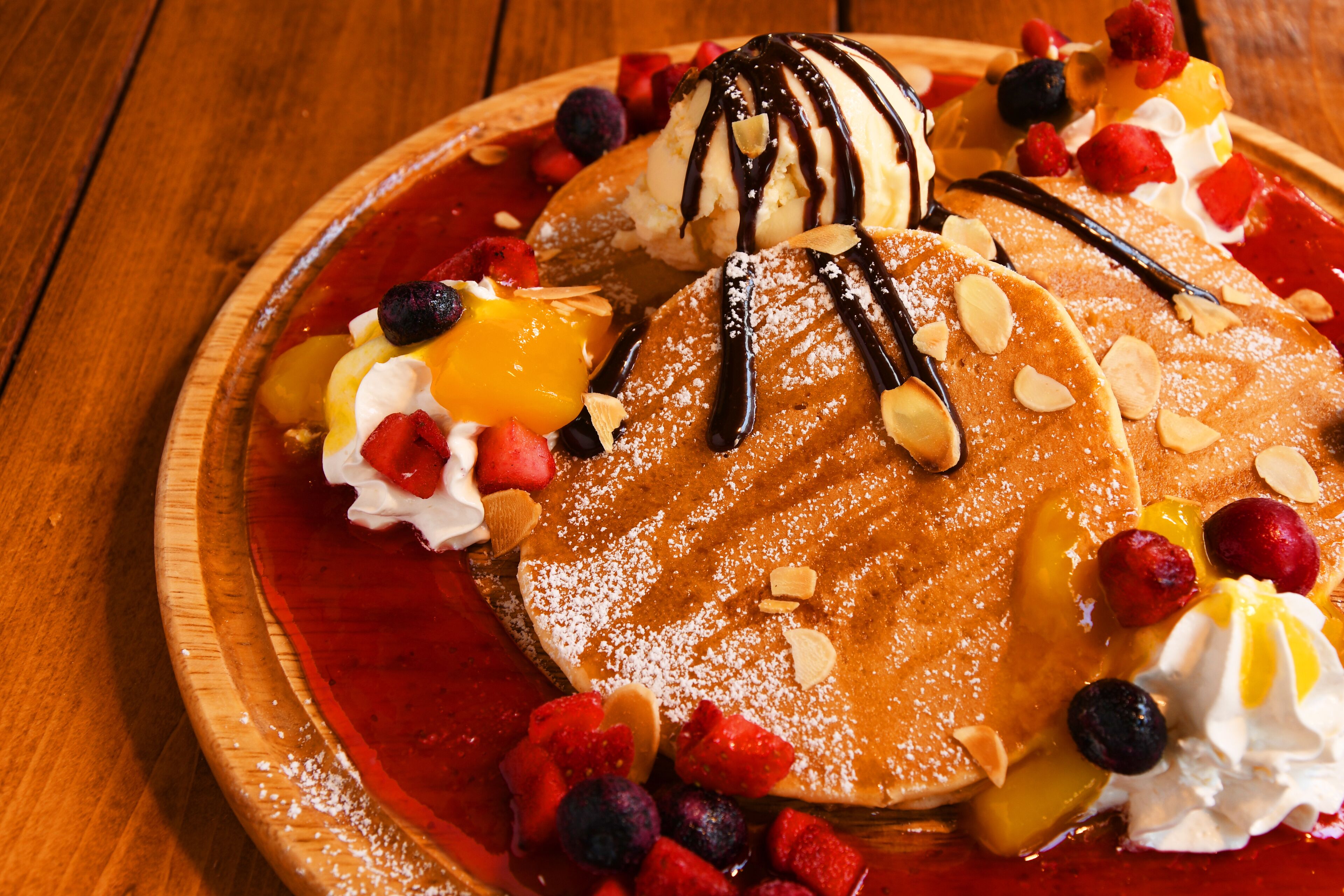 Une assiette de dessert avec des crêpes, de la glace et divers fruits.