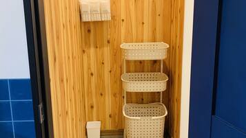 Una habitación pequeña de madera con un muro de madera, un toallero blanco y tres cestas color beige.