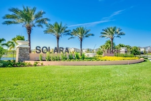 Une enseigne portant l’inscription « SOLARA », entourée de palmiers et d’une pelouse bien entretenue.