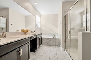 A modern bathroom with a large mirror, a double sink vanity, a bathtub, and a glass shower enclosure. - Burma Villa Reunion (Kissimmee)