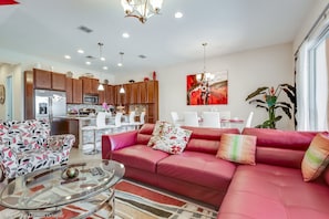 A modern living room with a red sofa, a patterned armchair, and a glass coffee table.