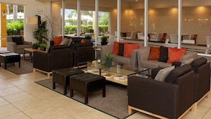 A modern lounge area with sofas, a coffee table, and large windows offering a view of the outdoors. - Secret Key Villa Emerald Island 1 (Kissimmee)