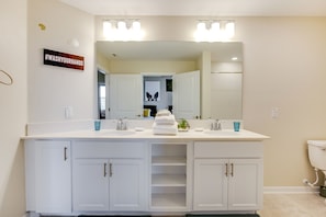 Un baño moderno con tocador doble, un espejo grande y un cartel que dice #WashYourHands.