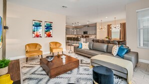 A modern living room with a sofa, two armchairs, a coffee table, and a dining area in the background. - Bookmark Villa Storey Lake (Kissimmee)