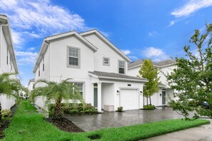 A modern two-story house with a garage, surrounded by well-maintained greenery and a paved driveway. - Amazing Storey Lake 5 Bedroom 5 Bathroom 4778kcc (Kissimmee)