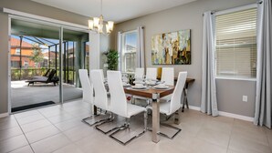 A modern dining area with a glass door leading to a balcony, a chandelier, and a dining table set for six.