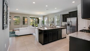 A modern kitchen with a central island, dark cabinetry, and stainless steel appliances.