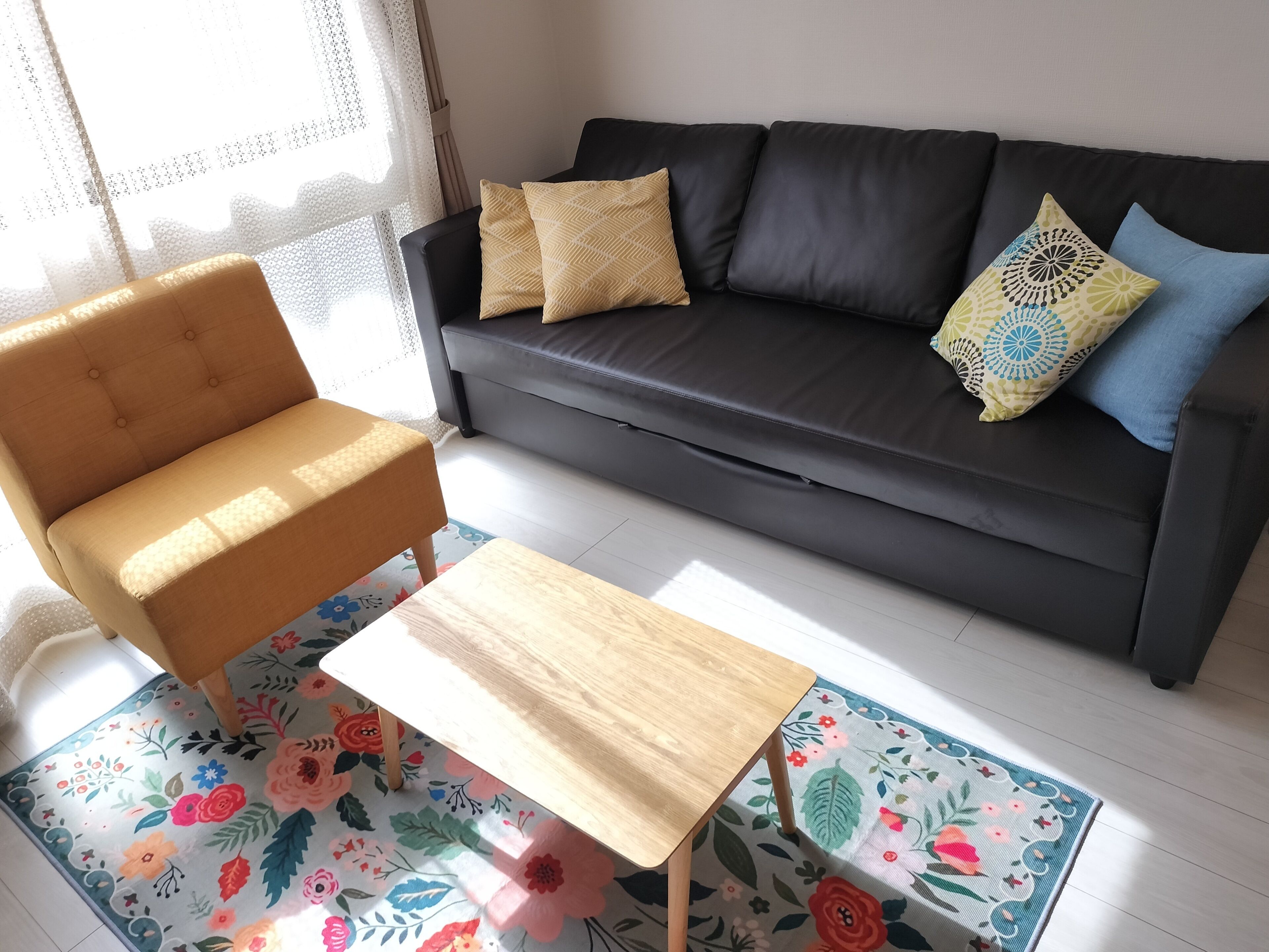A living room with a sofa, a chair, a coffee table, and a floral rug.