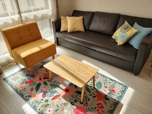 A living room with a brown sofa, a wooden coffee table, and a floral rug.