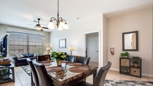 A dining area with a marble table, leather chairs, and a ceiling fan. - Butterway Villa Windsor Hills (Kissimmee)