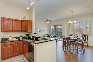 A spacious kitchen with wooden cabinets, a central island, and a dining area with a chandelier. - 4 Miles to the Magical World of Disney (Kissimmee)