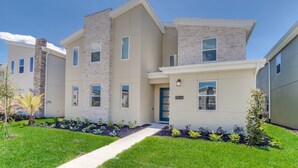 A modern two-story residential building with a stone facade, a blue door, and a well-maintained lawn. - 4559naluxury Lake View 8 BR Villa With Games Room (Kissimmee)