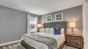 A bedroom with a large bed, two bedside lamps, and a headboard. - 4559naluxury Lake View 8 BR Villa With Games Room (Kissimmee)