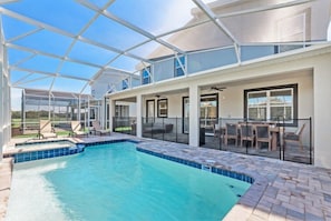 Une piscine extérieure couverte avec un toit en verre, un espace patio aménagé avec du mobilier d’extérieur, et une vue sur le paysage environnant.