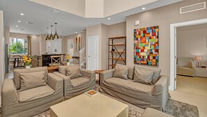 Un salon moderne avec des canapés de couleur beige, une table basse et un tableau abstrait aux couleurs vives.