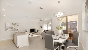 Una cocina y comedor modernos con una isla central, una mesa de comedor con sillas y un ventilador de techo.
